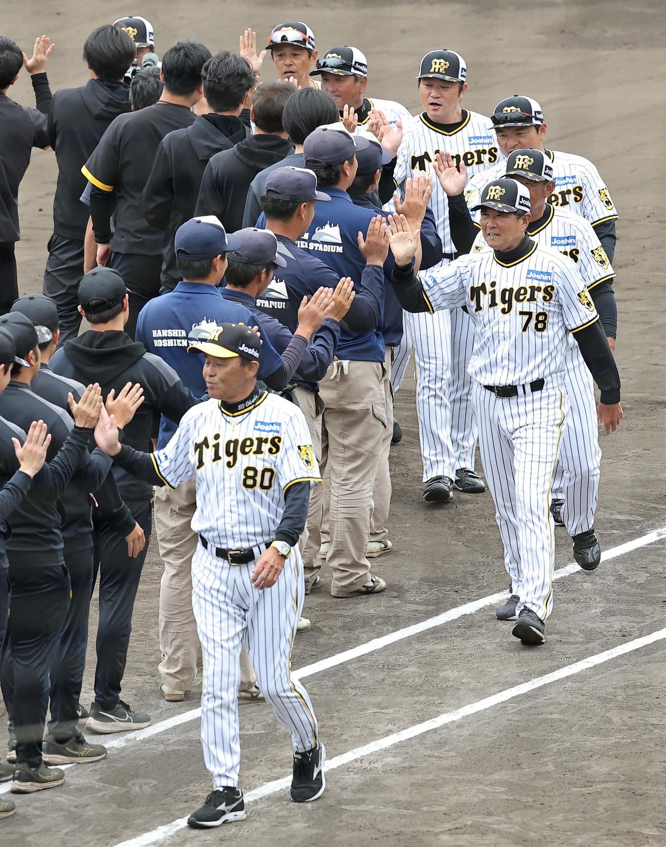 春季キャンプを終えた岡田監督（左）は関係者とハイタッチする（撮影・上田博志）