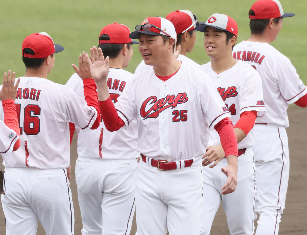 沖縄キャンプ終了で、ナインらとハイタッチする広島新井監督。右は高木（撮影・加藤孝規）