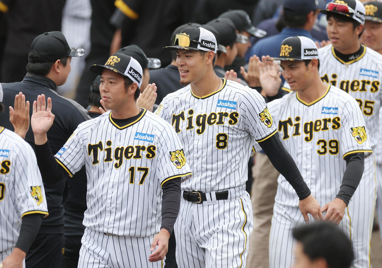 春季キャンプを打ち上げ、スタッフらとハイタッチを交わす阪神佐藤輝（中央）。左は青柳、右は栄枝（撮影・前田充）