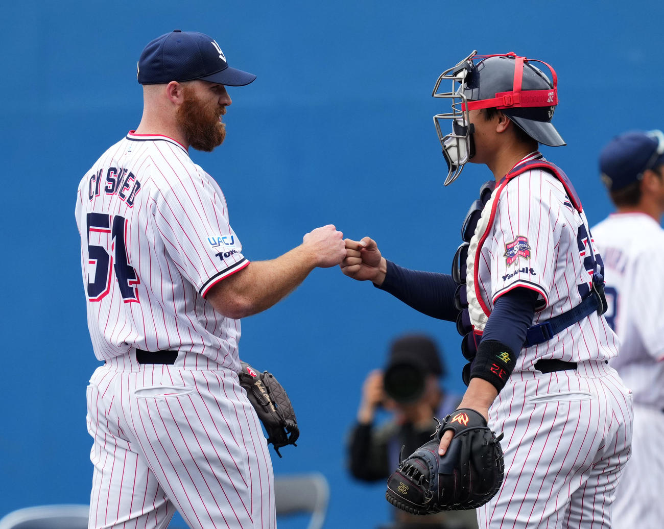 ヤクルト対起亜　1回表を無失点に抑えタッチを交わすヤクルト先発のサイスニード（左）と松本直（撮影・横山健太）