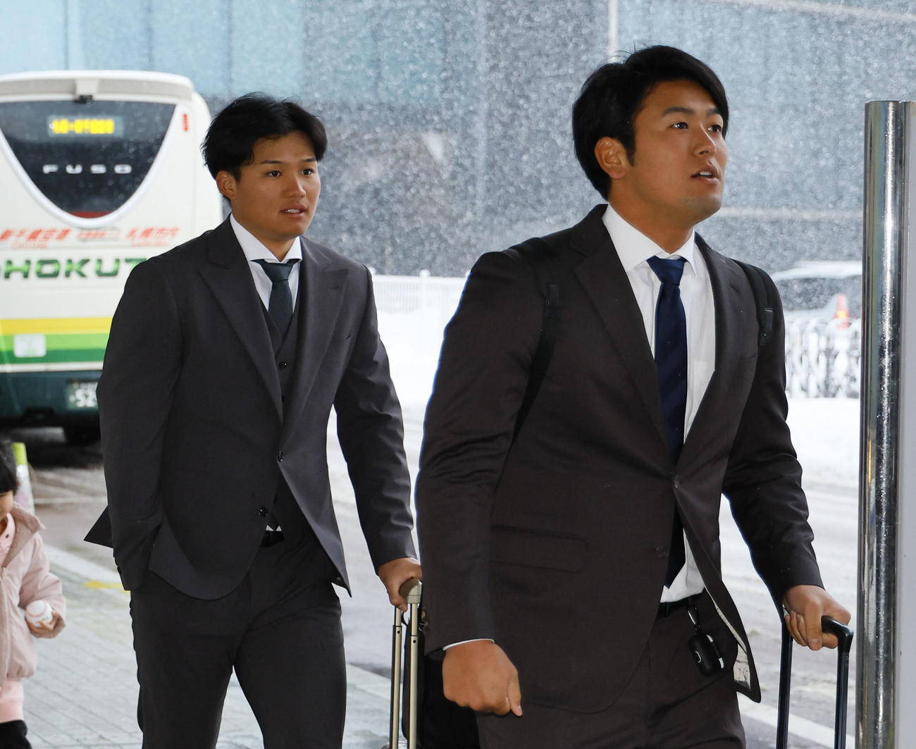 北海道に到着し、雪がふぶく中バスに向かう岡留（右）と森下（撮影・藤尾明華）