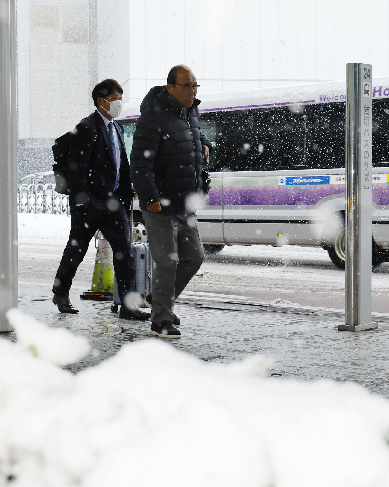 札幌に到着し、雪が吹雪く中バスに向かう阪神岡田監督（撮影・藤尾明華）