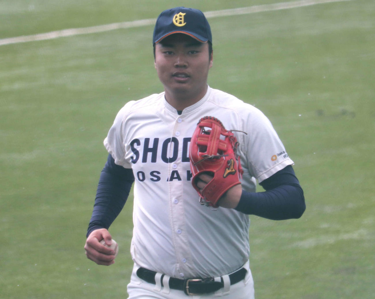 雪の舞う中、大商大での実戦デビューを果たした真鍋慧（新1年＝広陵）は攻守交代時に右翼手のキャッチボール役を担い、体を温めた（撮影・中島麗）