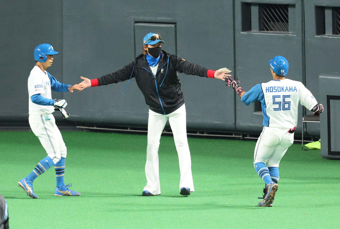 日本ハム対阪神　5回裏、日本ハム中島と細川を出迎える新庄監督（中央）（撮影・佐藤翔太）