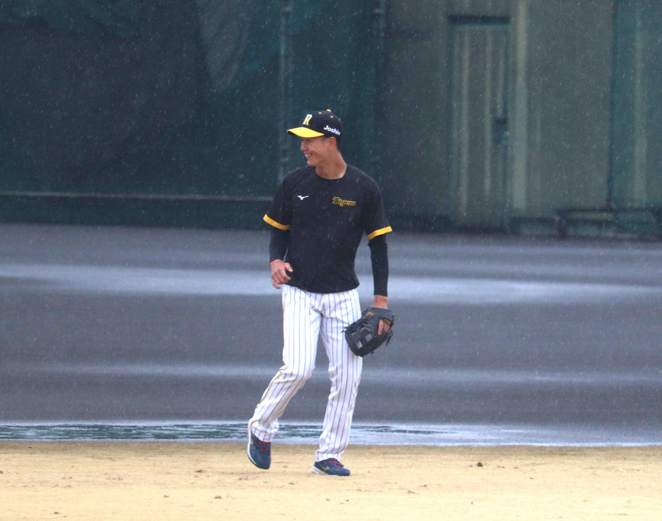 雨の中、屋外で笑顔で練習する阪神山田脩也（撮影・中島麗）