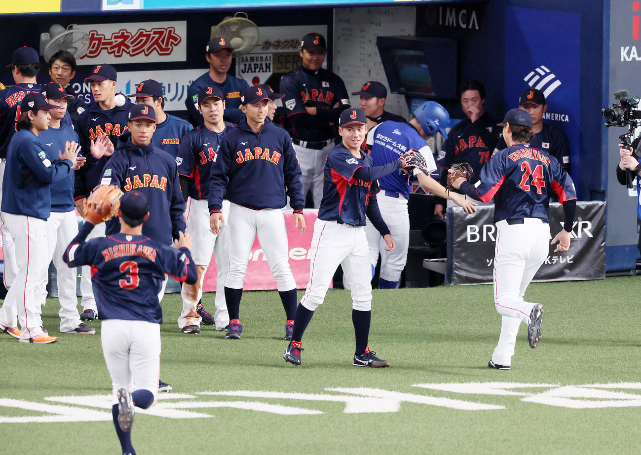 欧州対日本　1回裏の欧州の攻撃を三者凡退に抑えた金丸（手前右から2人目）はベンチ前で野手を迎える（撮影・加藤哉）