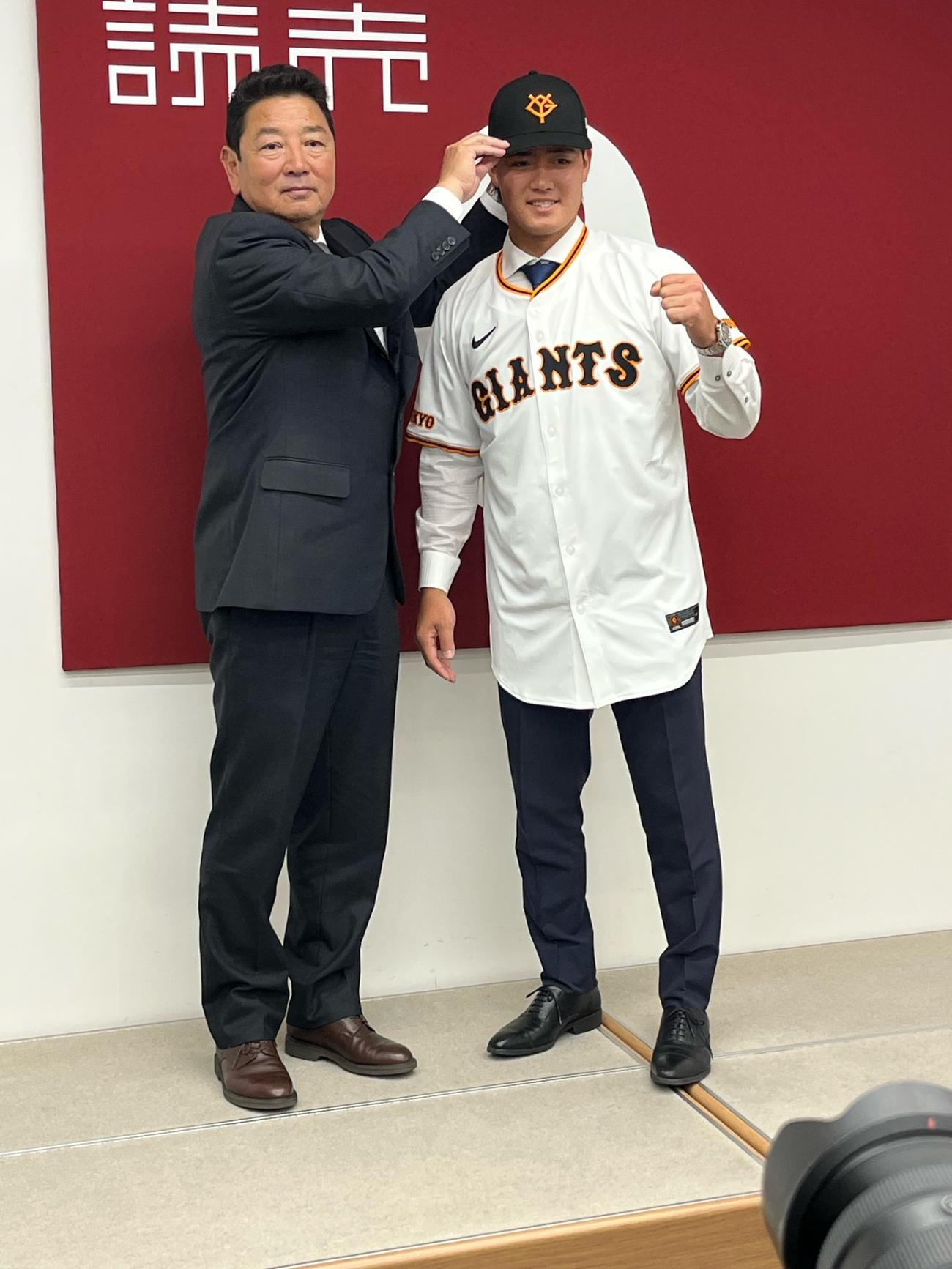 日本ハムからトレード移籍した巨人郡（右）は入団会見で吉村編成本部長に帽子をかぶせてもらい、笑顔を見せる