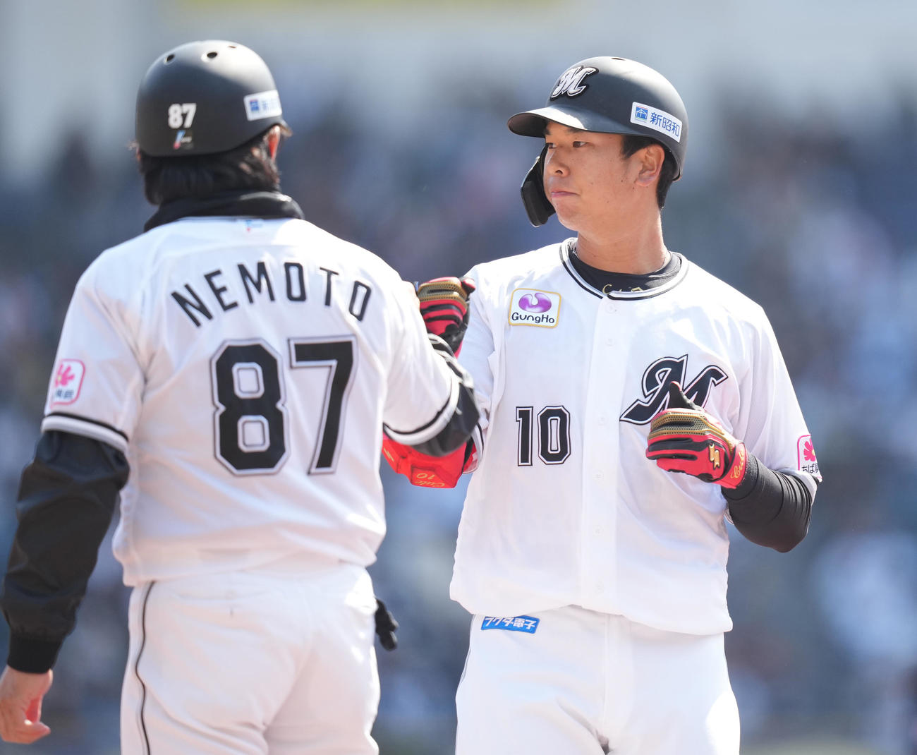ロッテ対オリックス　1回裏ロッテ1死、中前打を放った上田（右）は根元コーチとタッチを交わす（撮影・鈴木みどり）