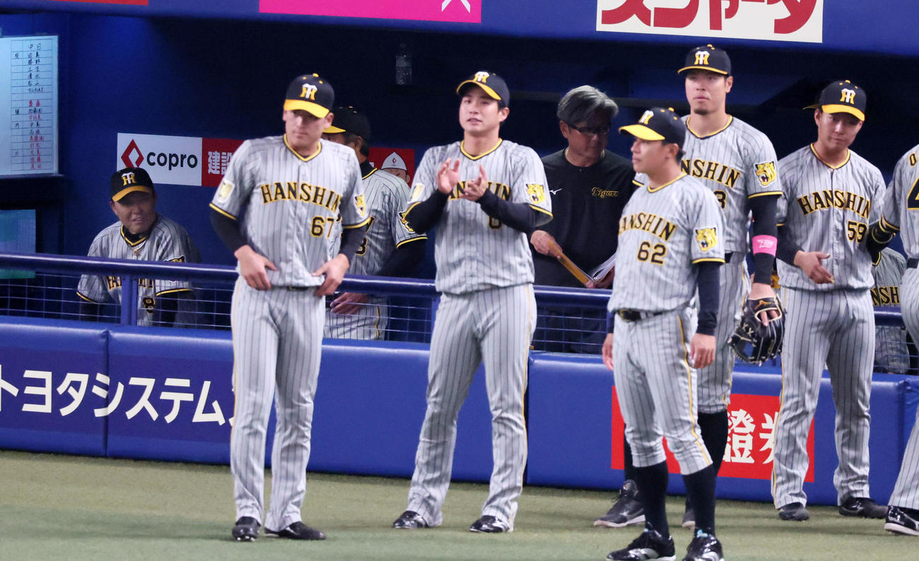 中日対阪神　2回裏を終えベンチ前でナインを迎える佐藤輝。左端は岡田監督（撮影・加藤哉）