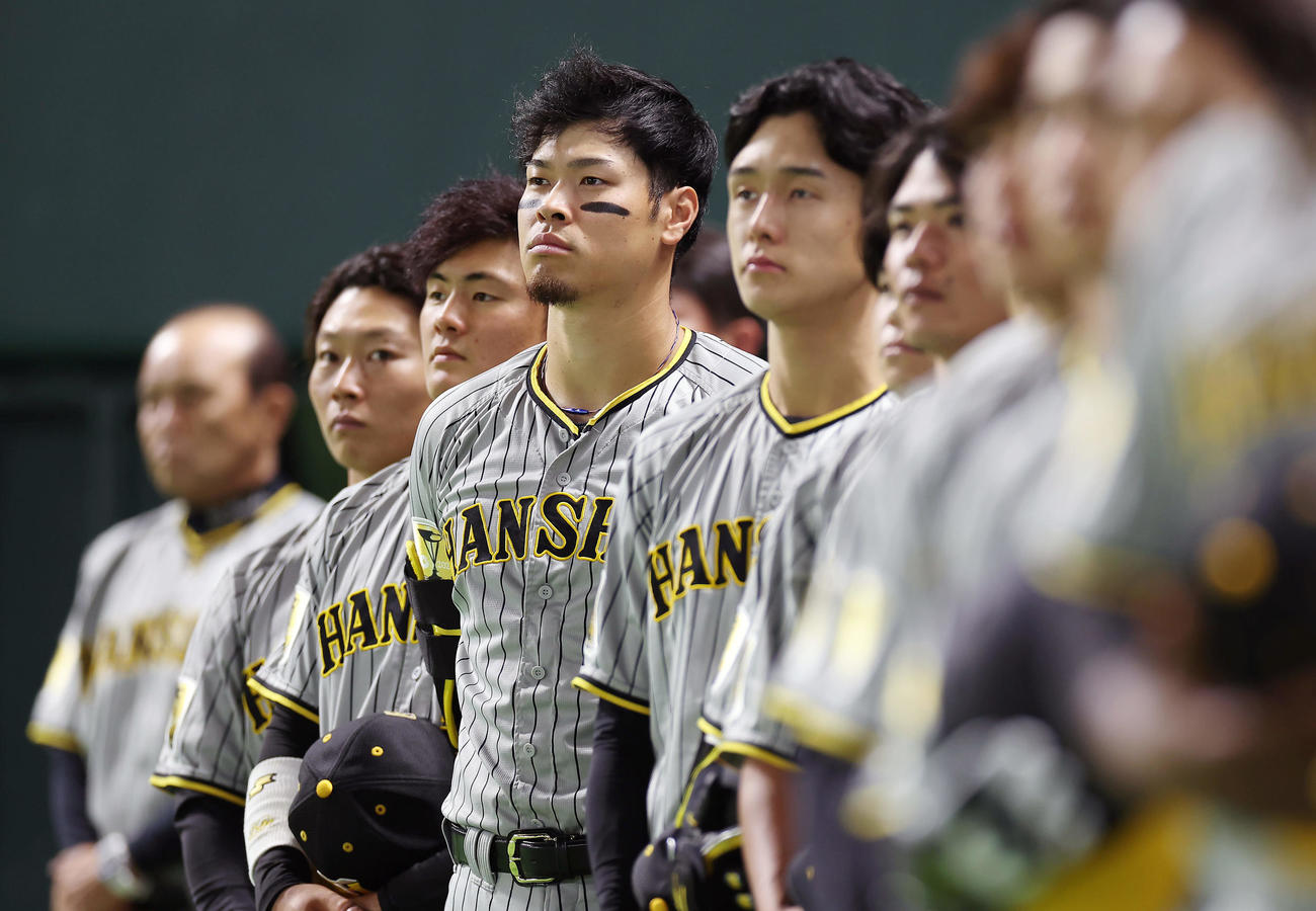 ソフトバンク対阪神　試合前、整列し君が代演奏を聞く阪神佐藤輝（中央）ら（撮影・前田充）