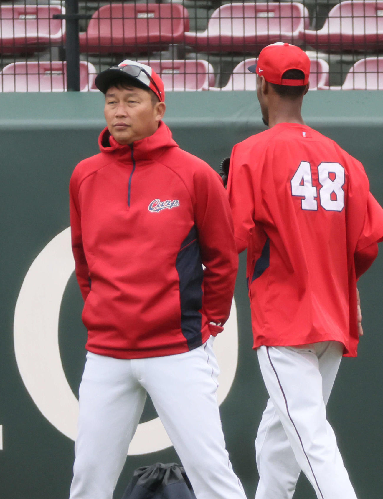 投手陣の練習を見守る新井貴浩監督。右はアドゥワ誠（2024年3月6日撮影）