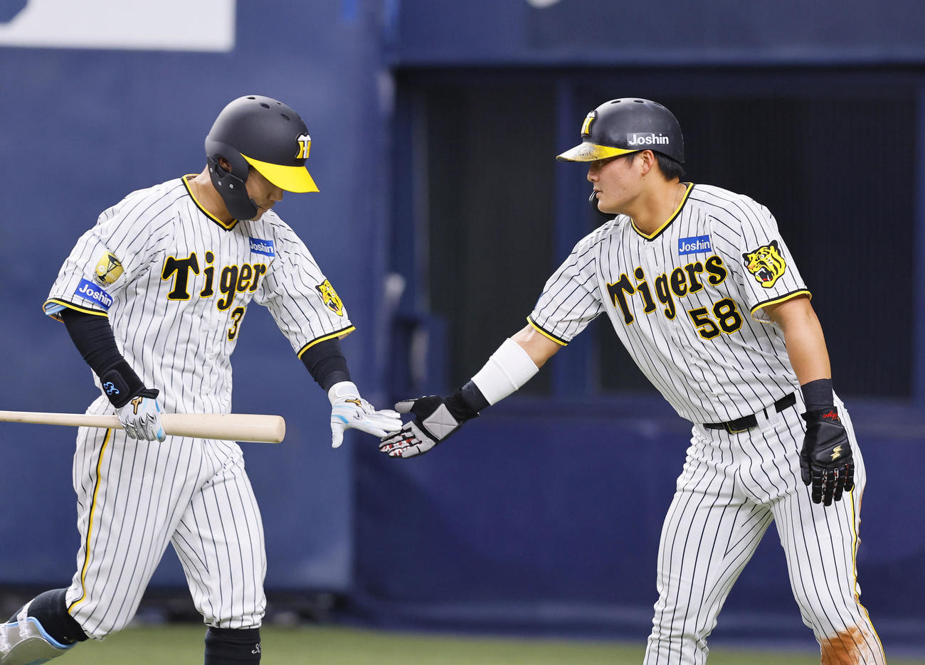 オリックス対阪神　4回裏阪神1死三塁、生還し、犠飛を放った糸原（左）とタッチを交わす前川（撮影・藤尾明華）