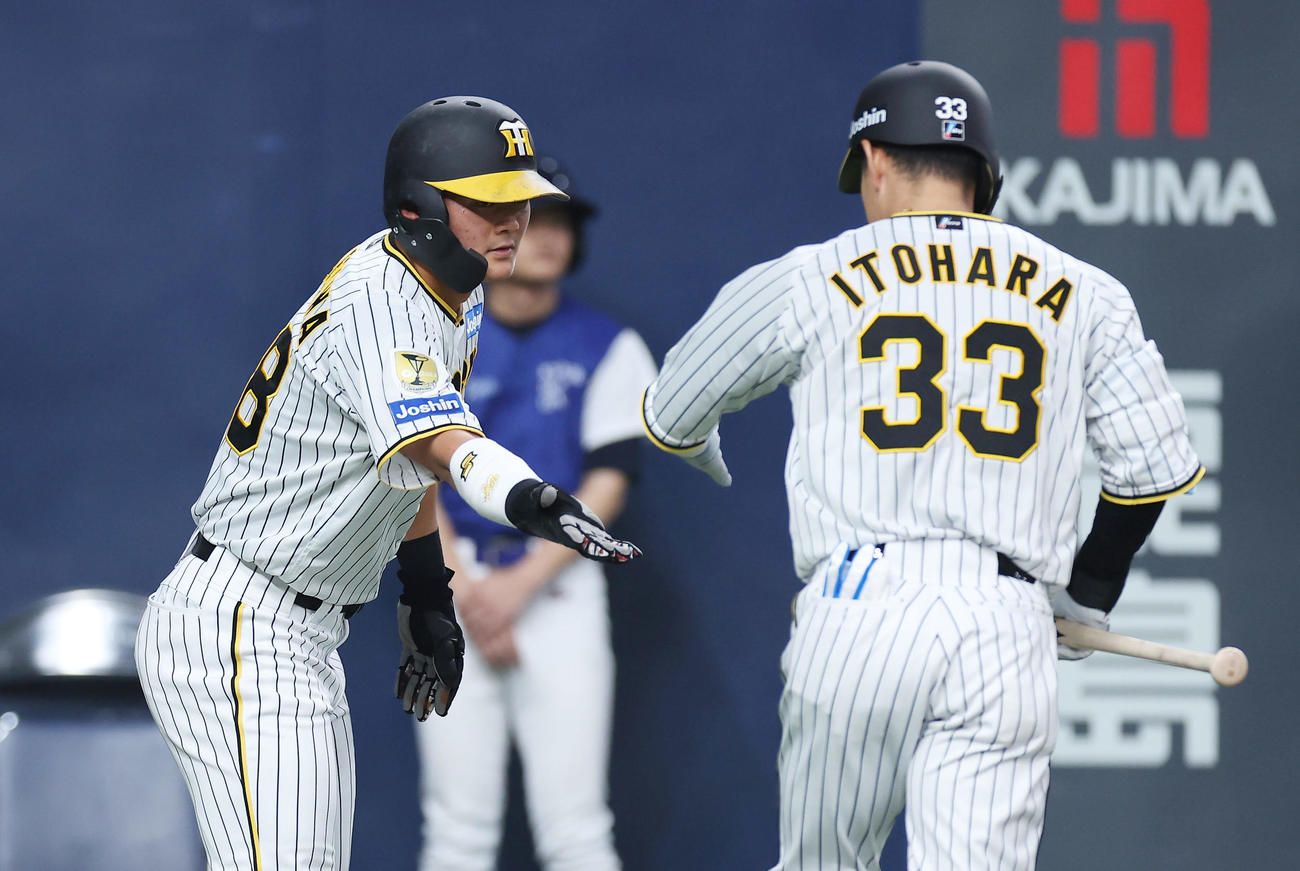 阪神対オリックス　4回裏阪神1死三塁、中犠飛を放った糸原（右）を迎える前川（撮影・前田充）