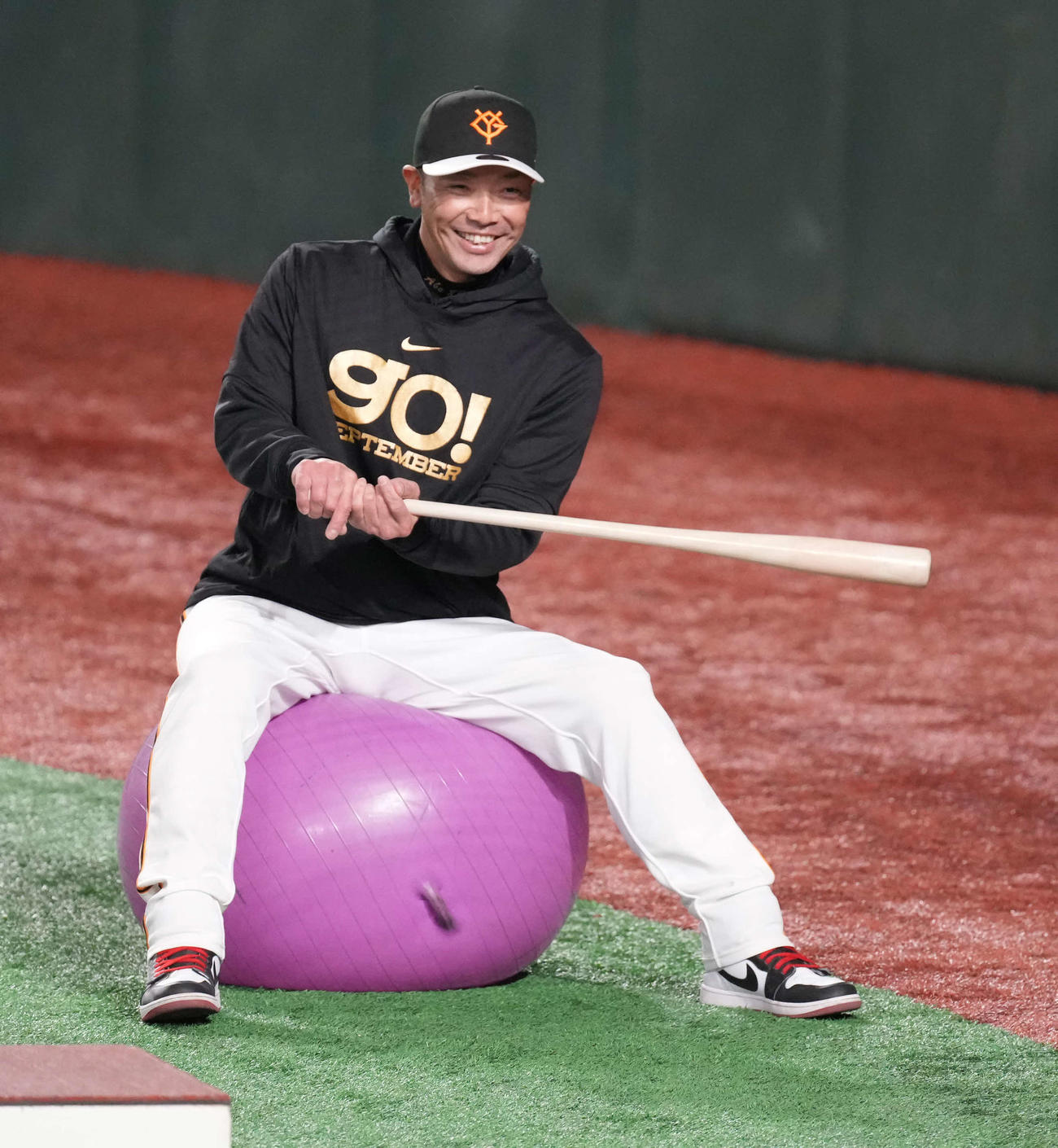 バランスボールに座りバットを手に笑顔を見せる巨人阿部監督（撮影・小沢裕）