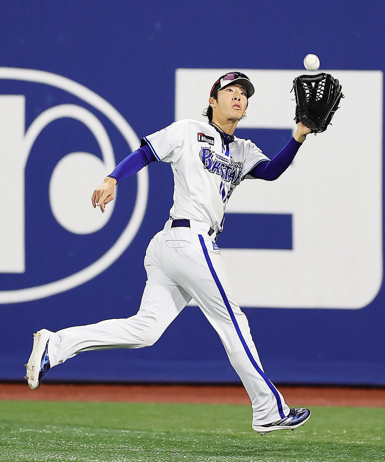 ナイター照明の下、外野ノックを受けるDeNA度会（撮影・足立雅史）
