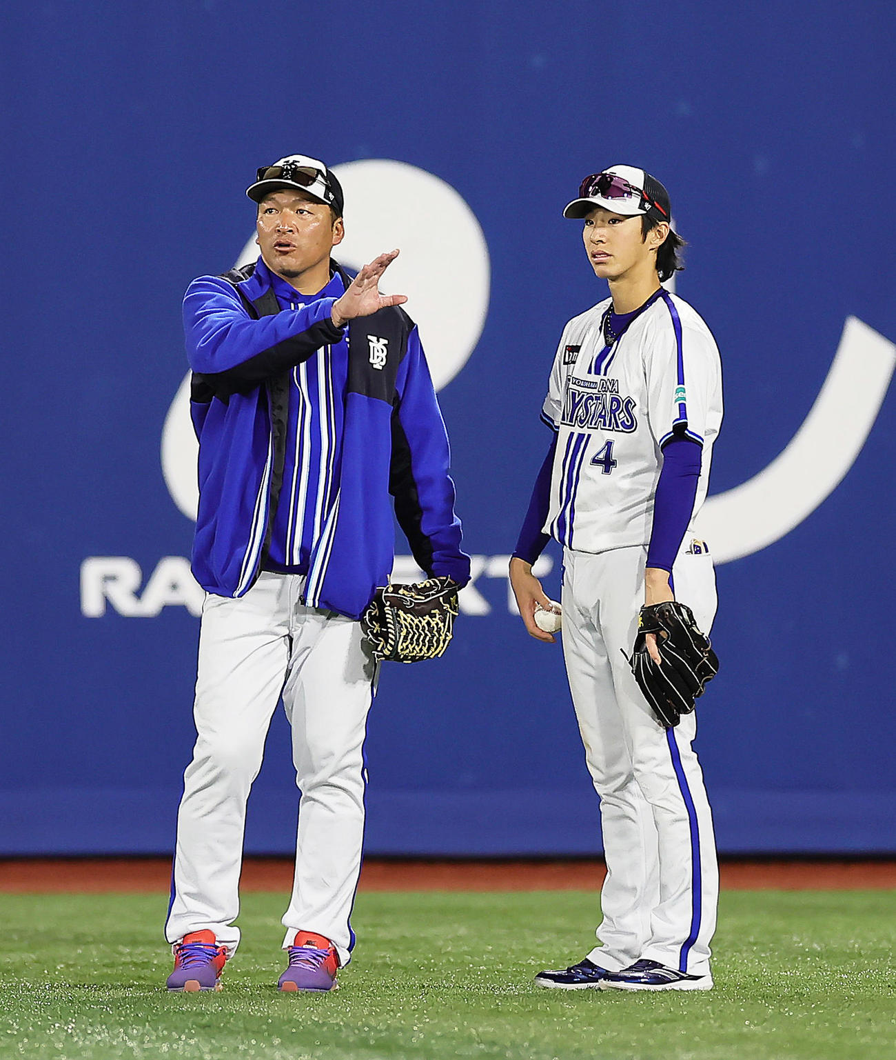 DeNA練習　DeNA小池コーチ（左）から外野で守備指導を受ける度会（撮影・足立雅史）