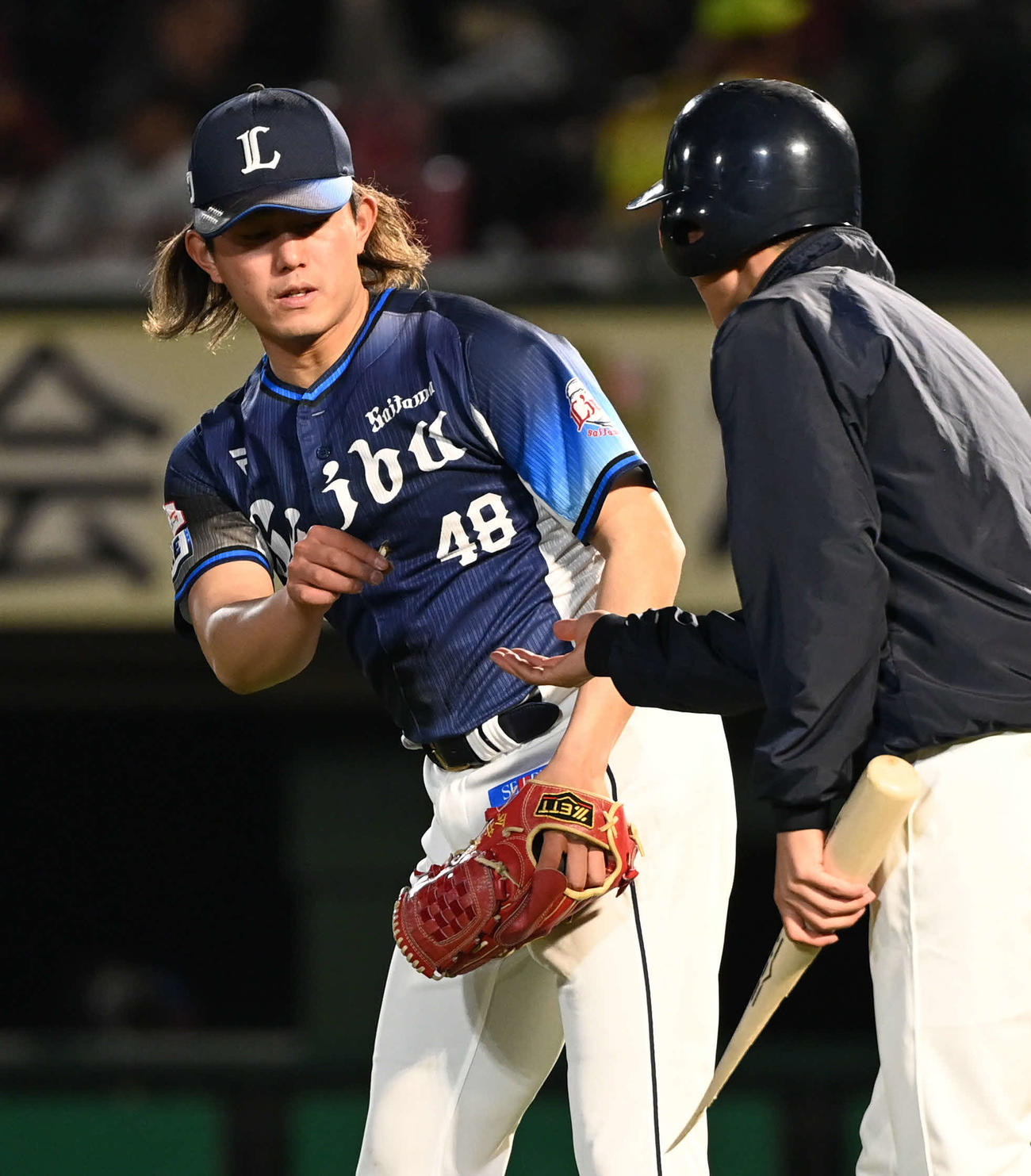 楽天対西武　6回裏楽天1死、今井は小深田が折ったバットの破片を拾う（撮影・山崎安昭）