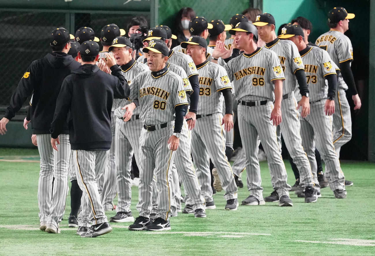 巨人対阪神　勝利球を手に、阪神の選手たちとタッチを交わす岡田監督（手前右）（撮影・江口和貴）