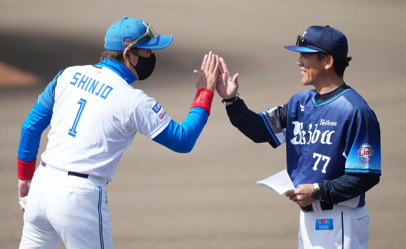3月7日　日本ハム対西武　試合前のメンバー表最終確認でハイタッチする日本ハム新庄監督（左）と西武松井監督