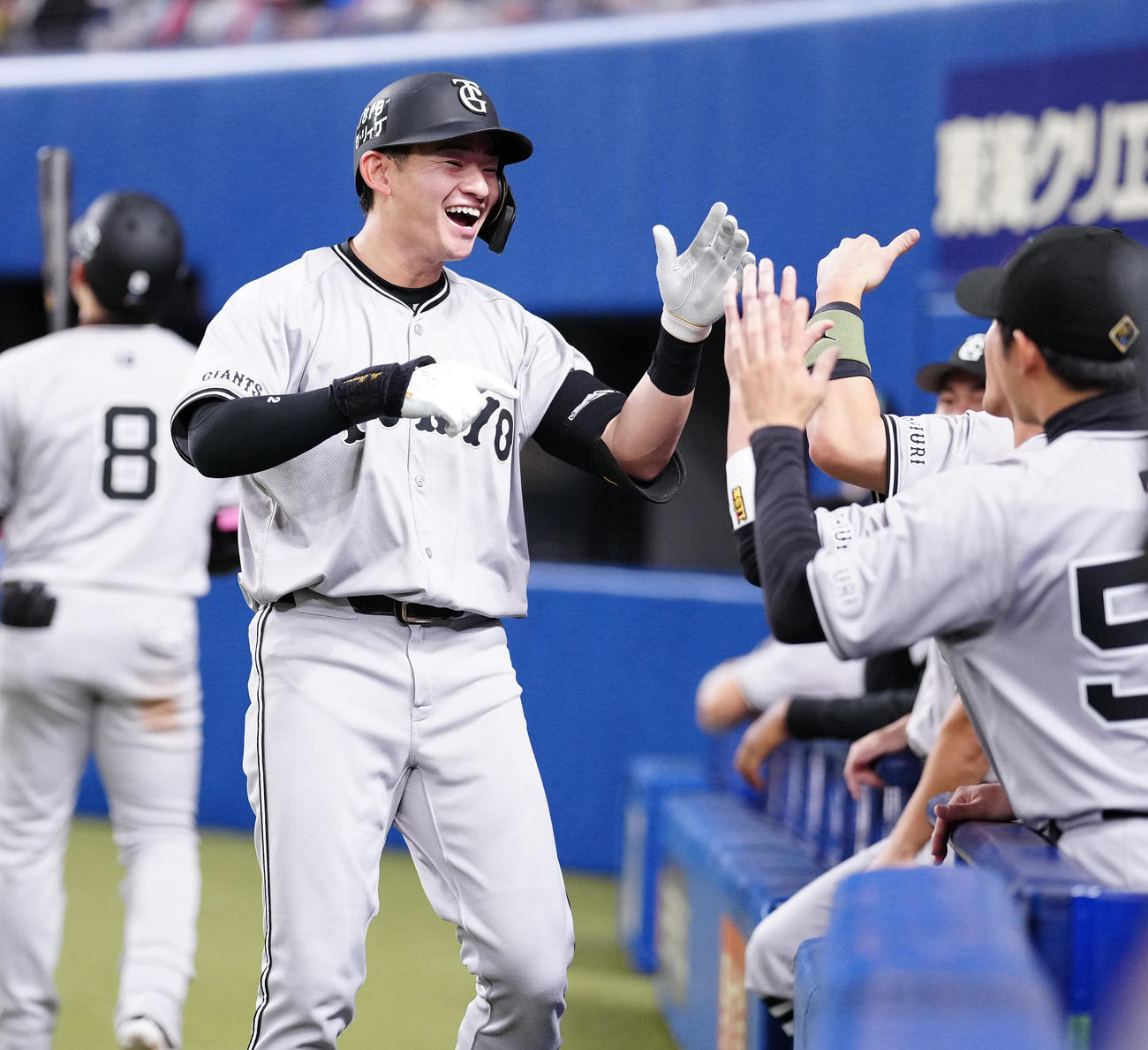 中日対巨人　8回表巨人1死、プロ初となるソロ本塁打を放ち笑顔でタッチを交わす萩尾（撮影・江口和貴）