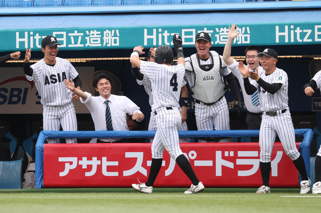 亜大対日大　1回裏亜大1死二、三塁、西川の適時打で生還した的場を出迎えるナイン（撮影・柴田隆二）