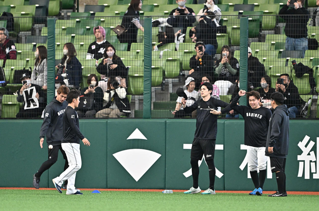 西武対ロッテ　完全試合を達成してちょうど２年がたち、「K」のパネルを手にするファンの前で調整するロッテ佐々木（左から3人目）（撮影・滝沢徹郎）