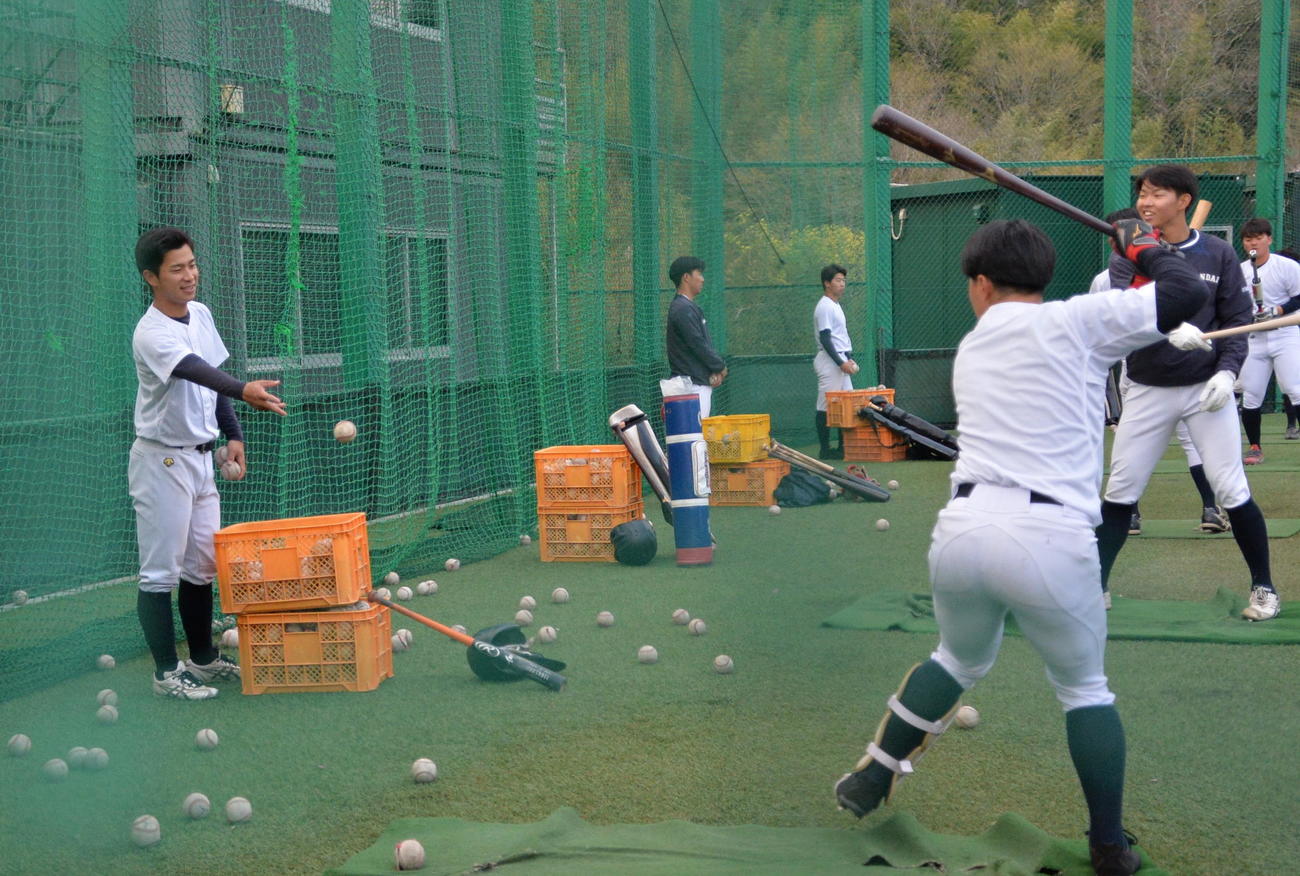トスバッティングのサポートをする仙台大・小田倉（左）（撮影・濱本神威）