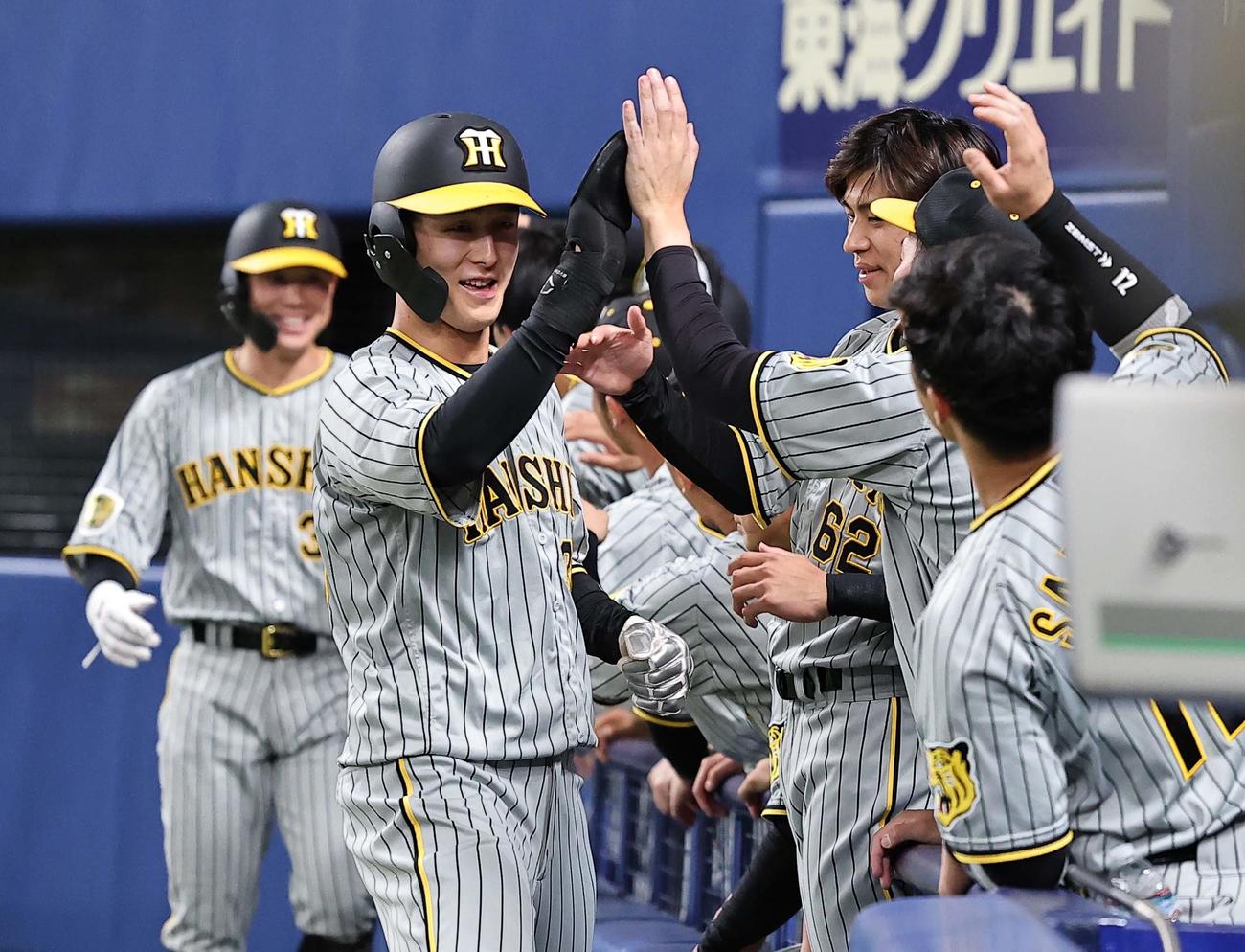 中日対阪神　8回表阪神2死二、三塁、近本の二塁適時内野安打で二塁から生還した小幡はナインと笑顔でハイタッチをする（撮影・上田博志）