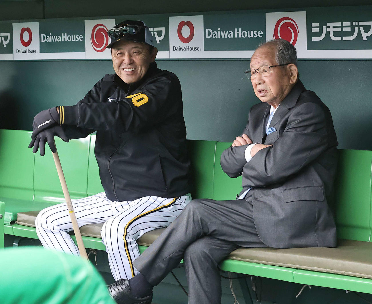 月9日、甲子園球場のベンチで話をする岡田監督（左）と吉田氏
