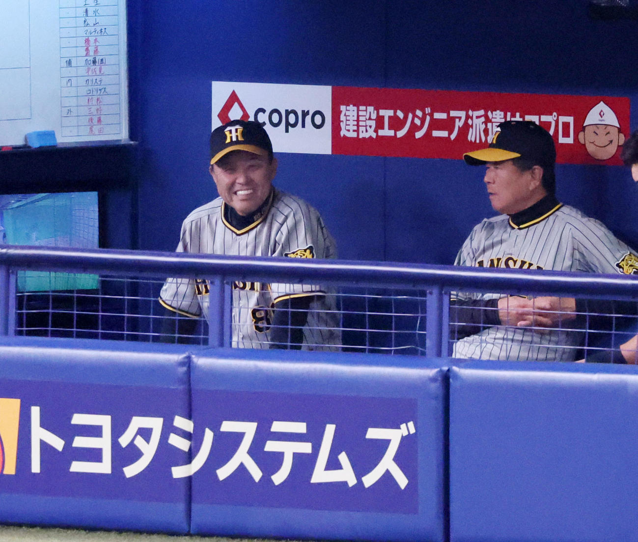 中日対阪神　6回裏を終えベンチで白い歯を見せる岡田監督。右は平田ヘッドコーチ（撮影・加藤哉）