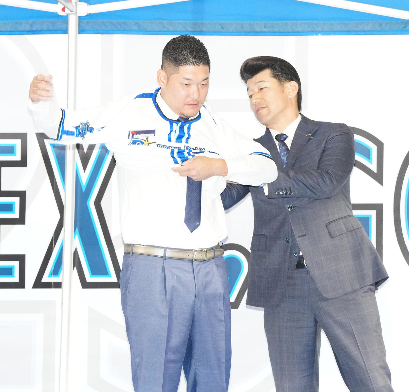 入団会見でDeNA三浦監督（右）からユニホームを渡され着用する筒香（撮影・江口和貴）