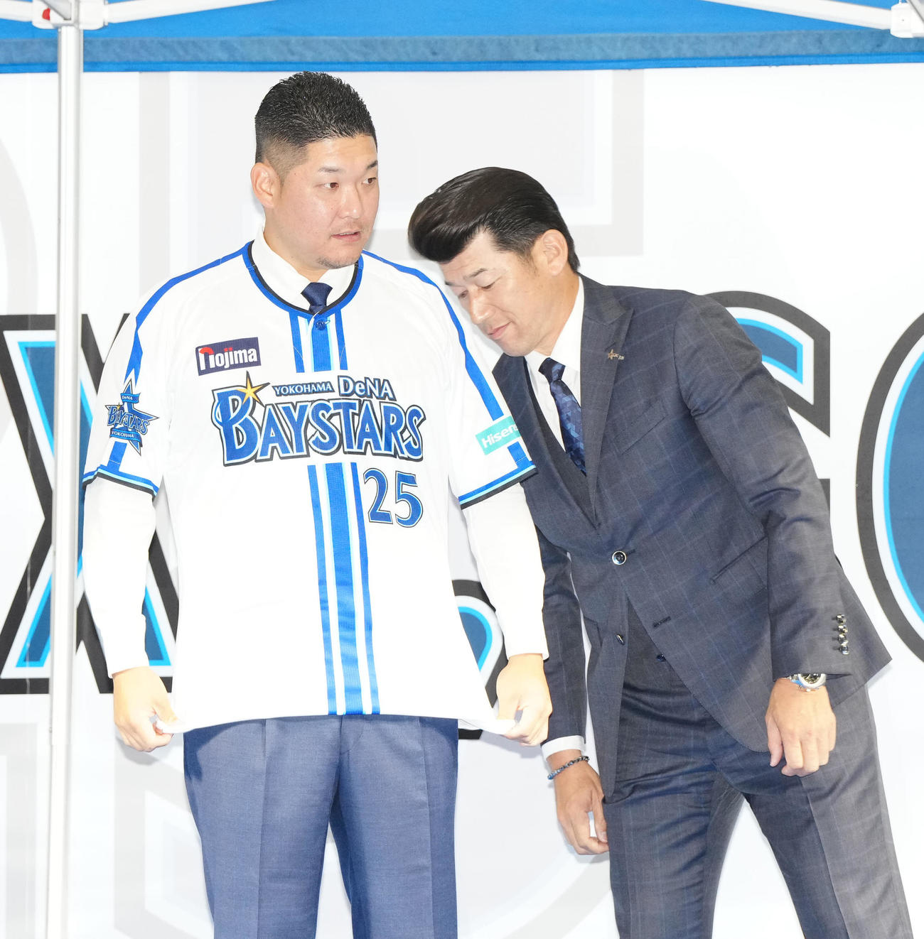入団会見でDeNA三浦監督（右）からユニホームを渡され着用した筒香（撮影・江口和貴）