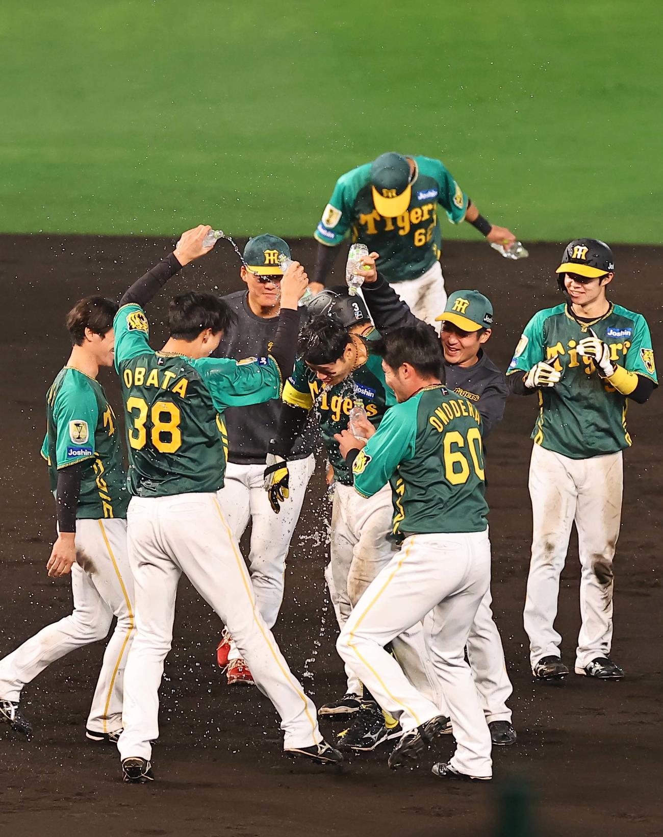 阪神対巨人　10回裏阪神無死満塁、サヨナラ安打を放った佐藤輝（中央）はナインからウオーターシャワーの祝福を受ける（撮影・上田博志）