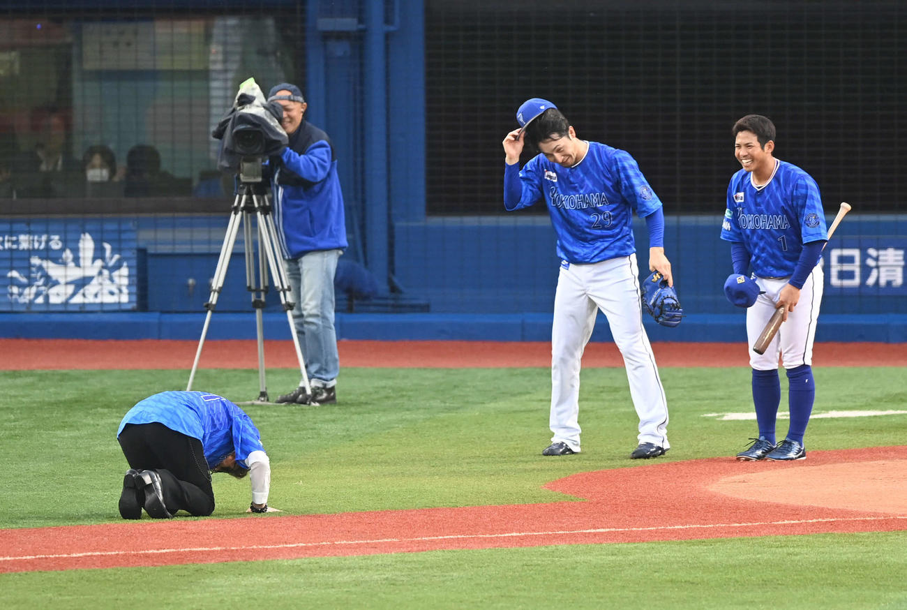 DeNA対阪神　セレモニアルピッチで投球した米米CLUBの大久保謙作が大暴投。石井竜也（左）は打席に立った桑原（右）と捕手を務めた伊藤光に土下座する（撮影・山崎安昭）