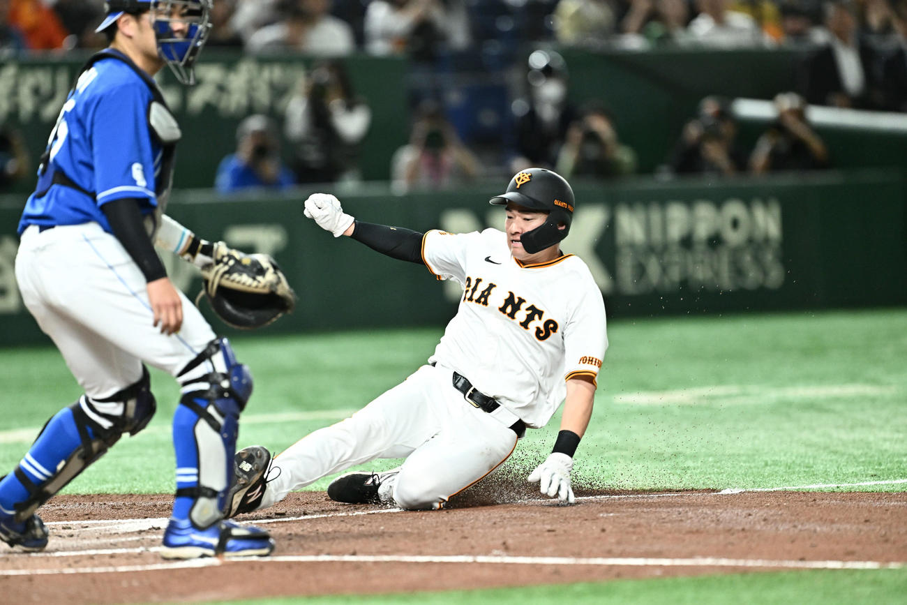 巨人対中日　2回裏巨人1死三塁、岸田の右犠飛で生還する萩尾（右）。捕手木下（撮影・滝沢徹郎）