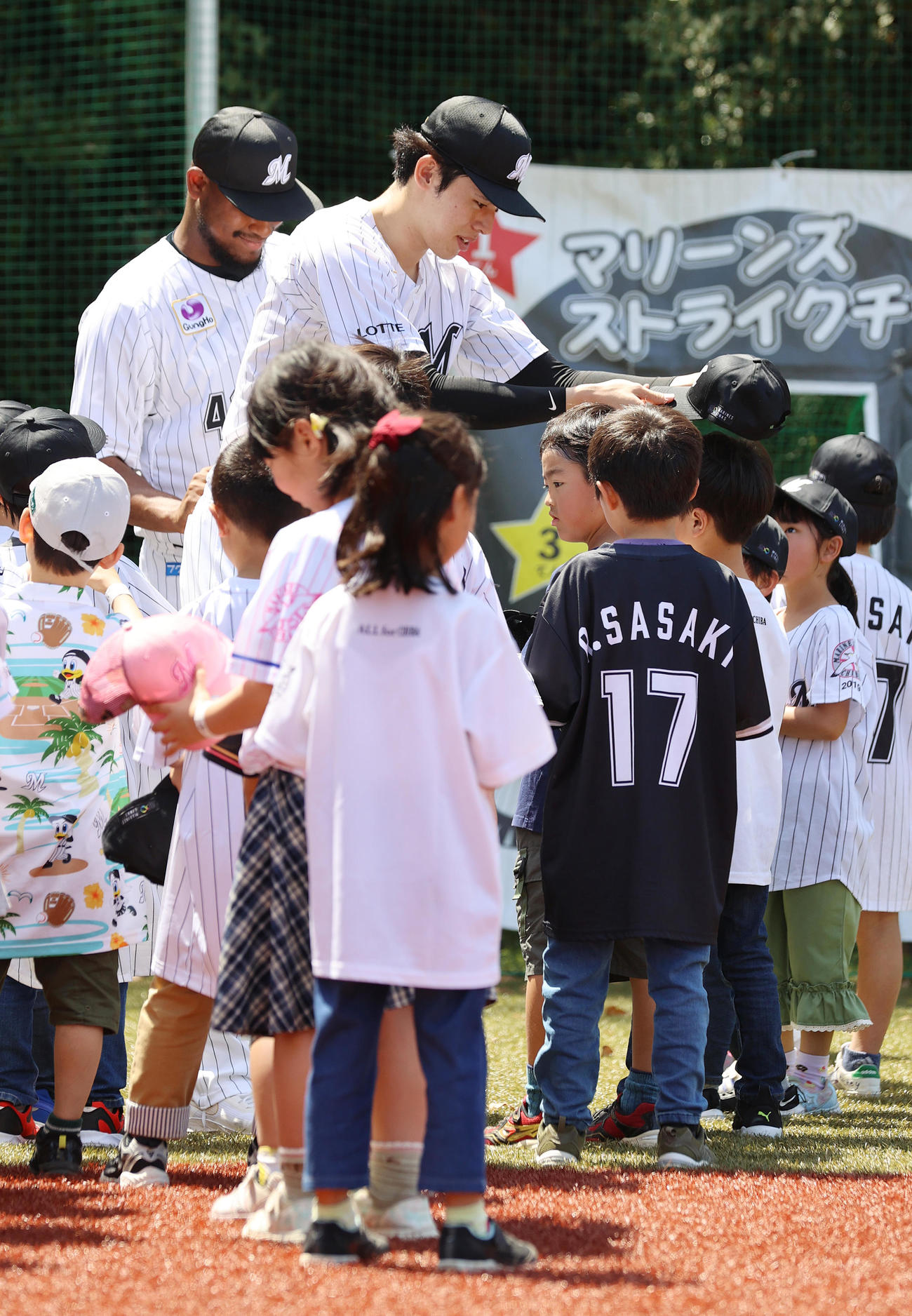 ロッテ対楽天　試合前のイベントで子どもたちに帽子をプレゼントするロッテ佐々木（中央）とメルセデス（後方）（撮影・河野匠）