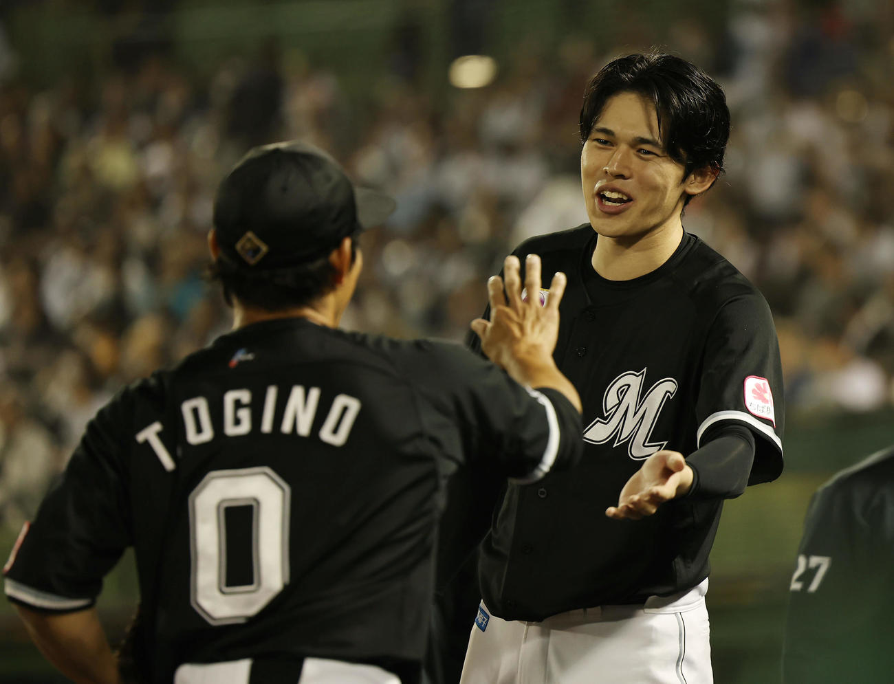 オリックス対ロッテ　8回裏を終え、ロッテ荻野（左）を笑顔で迎える佐々木（撮影・前田充）