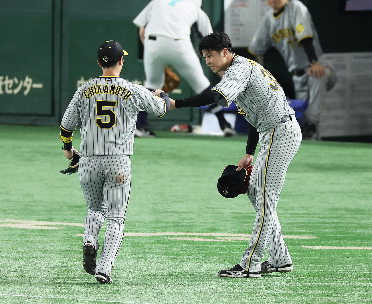 巨人対阪神　4回裏巨人2死三塁、坂本の打球を好捕した中堅手近本（左）をタッチで迎える才木（撮影・足立雅史）