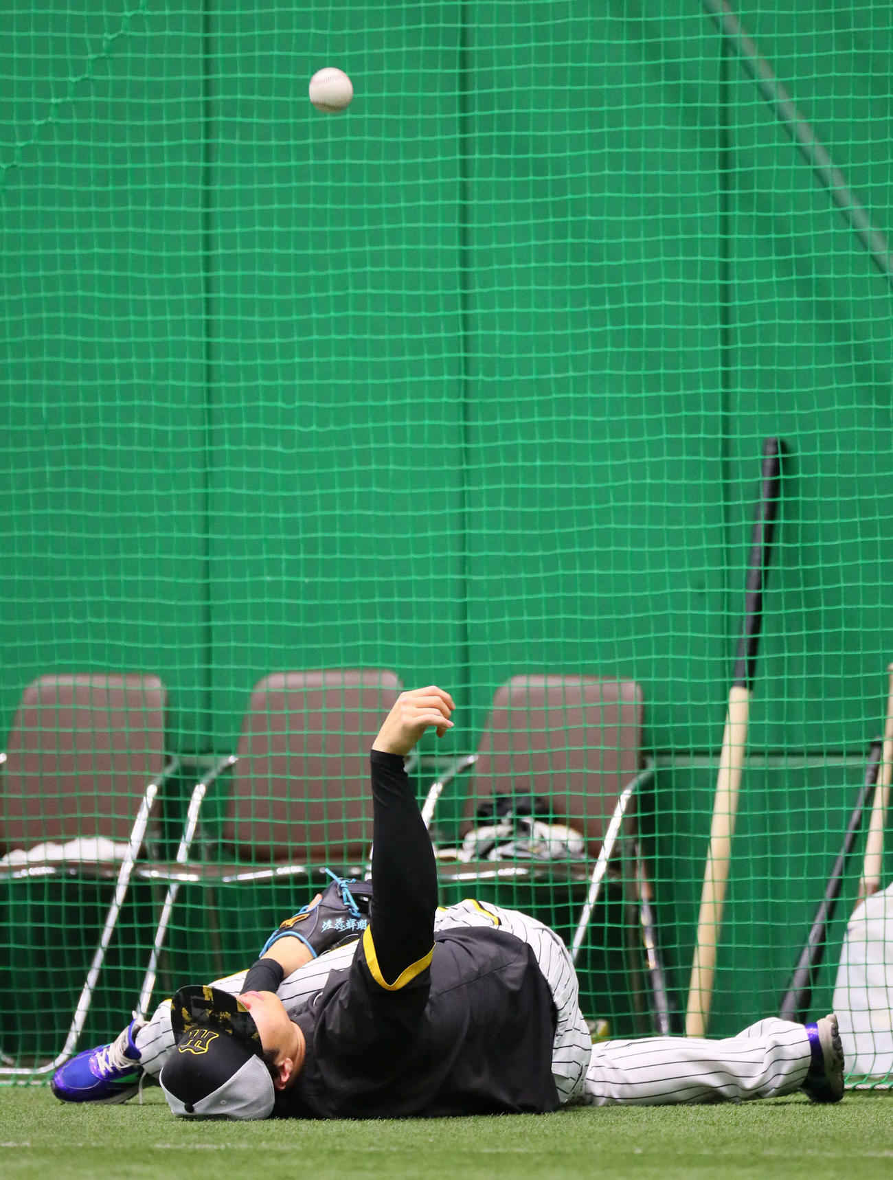 ストレッチしながら天井にスナップスローする佐藤輝（撮影・宮崎幸一）