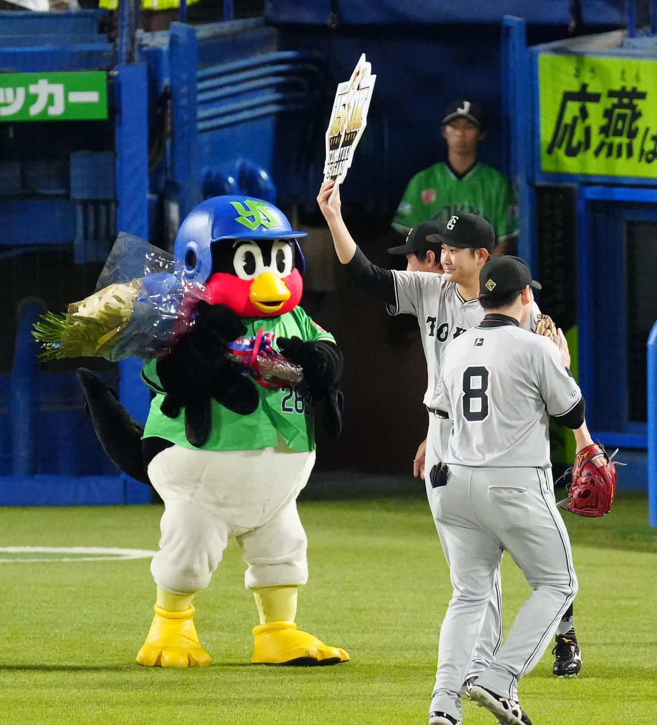 ヤクルト対巨人　6回裏終了後、1500奪三振で記念ボードを掲げる巨人菅野（右中央）。左は花束を持つつば九郎（撮影・江口和貴）
