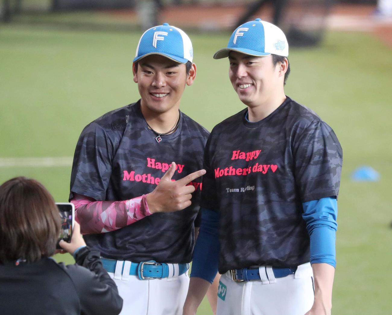 日本ハム対ロッテ　母の日のTシャツとアームカバーを付けて写真を撮る野村（左）と田中正（撮影・黒川智章）