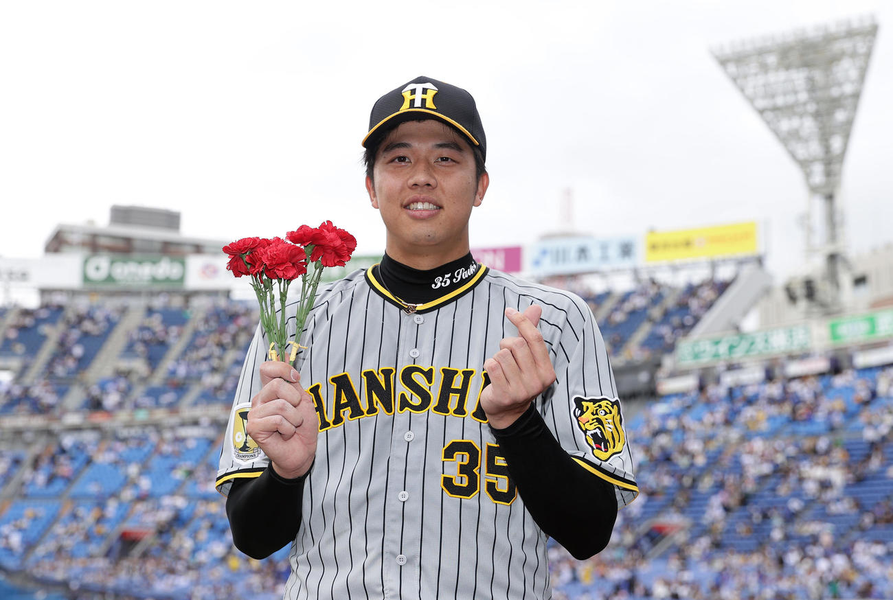 DeNA対阪神　DeNAに完封勝利を飾り、カーネーションを手に笑顔でポーズをとる阪神才木（撮影・前田充）