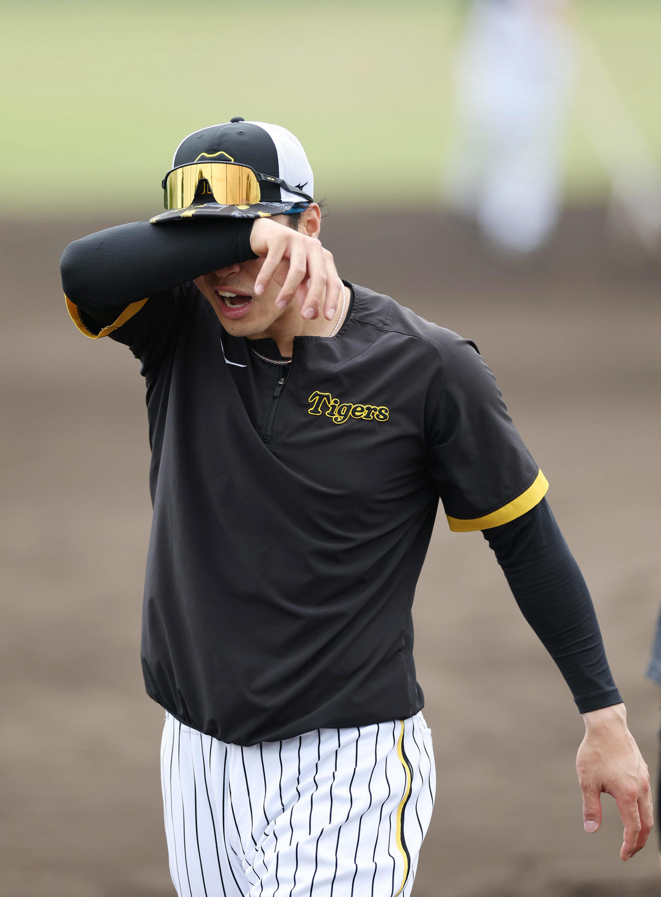 ノックの合間に汗をぬぐう阪神佐藤輝（撮影・前田充）