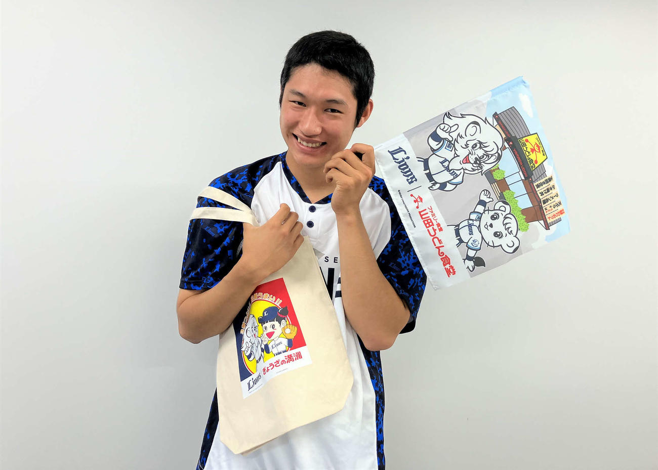 コラボグッズを持つ西武羽田（球団提供）