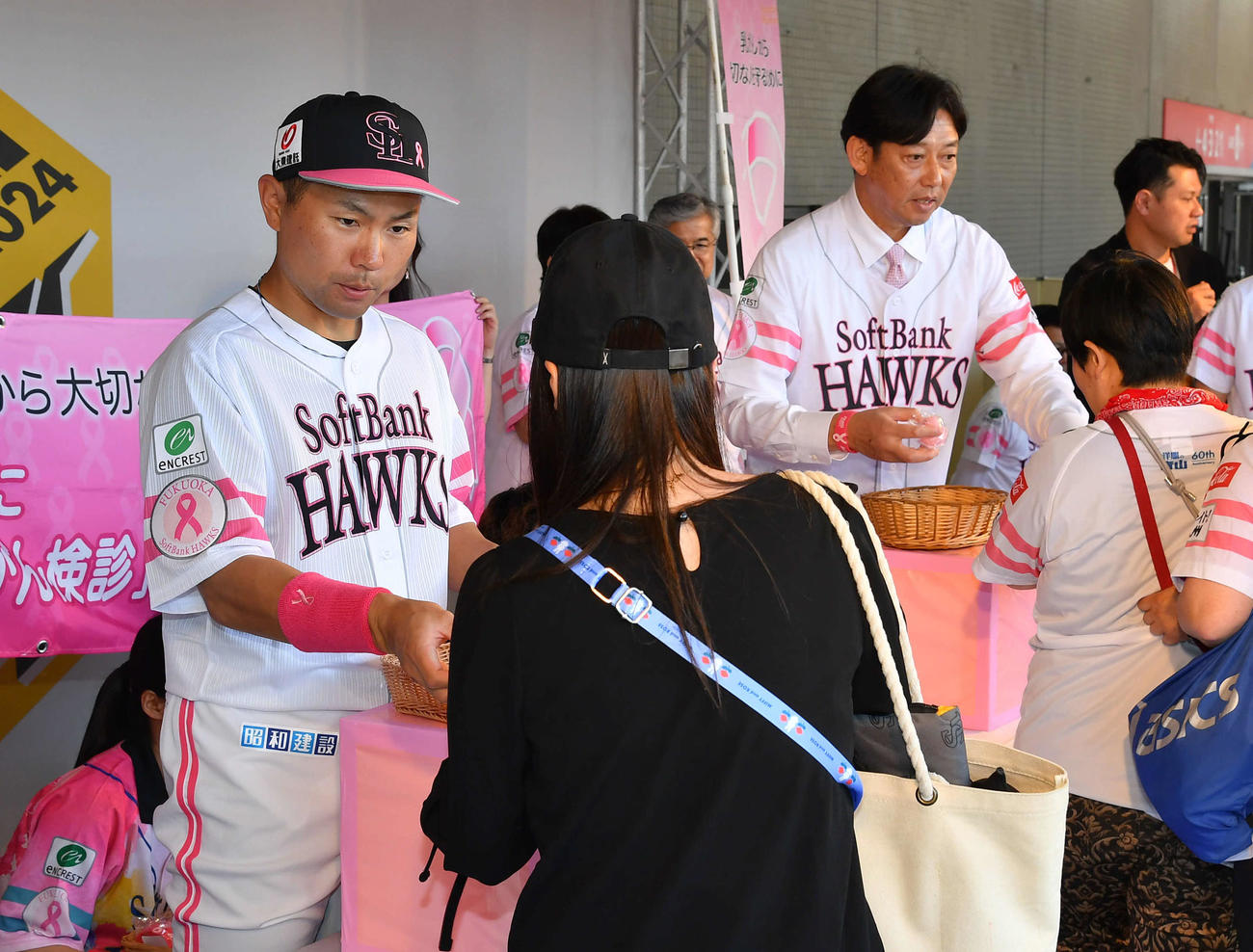 ソフトバンク対西武　ピンクリボン運動のグッズをファンに手渡しする中村晃（左）と鳥越裕介氏（撮影・岩下翔太）