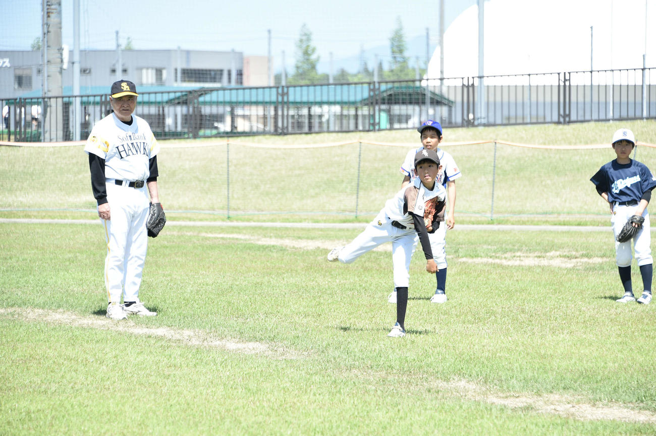 小学生の投球を見守る今井雄太郎氏（左）