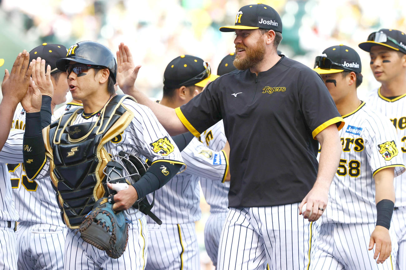 阪神対ヤクルト　今季初登板で勝利を挙げた阪神ビーズリー（手前右）は仲間と笑顔でタッチをかわす（撮影・上山淳一）