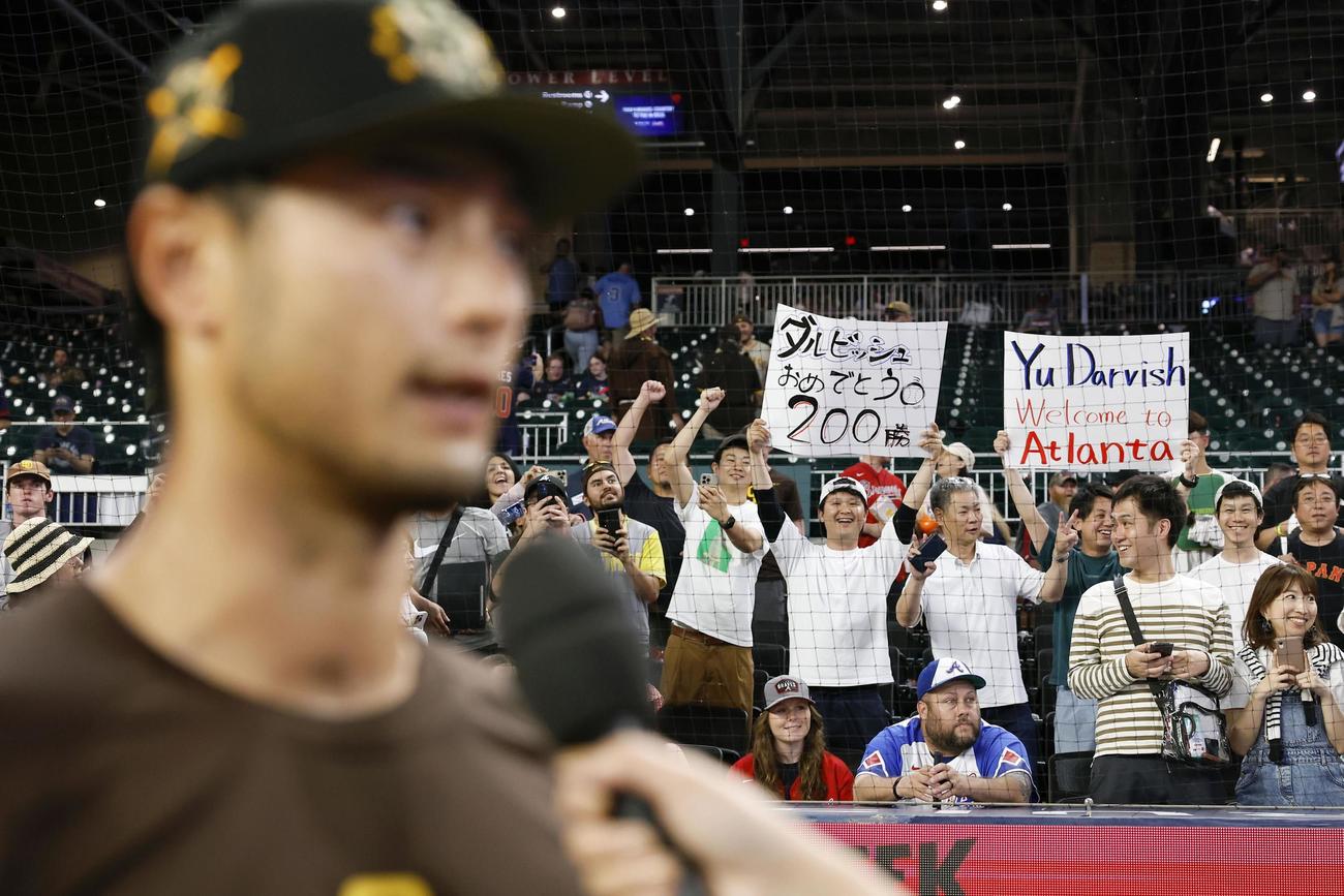 日米通算200勝を達成してインタビューに答えるパドレスのダルビッシュ（手前）に声援を送るファン（共同）
