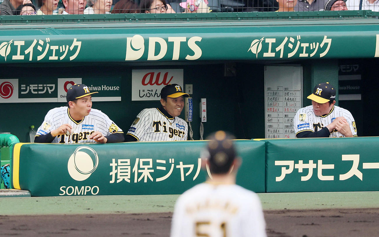 阪神対巨人　2回表巨人無死一塁、長野久義のファウルボールがベンチの中へ飛び込み白い歯を見せて避けた岡田監督。左は井上、右は安藤コーチ（撮影・加藤哉）