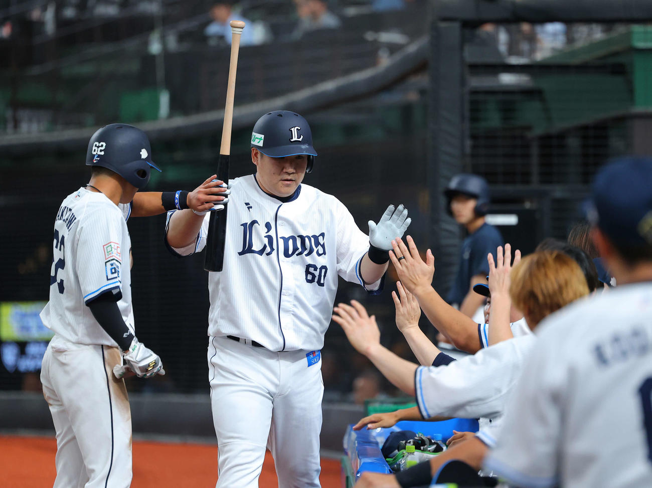 西武対オリックス　1回裏西武1死一、三、中犠飛でベンチに戻り、生還した滝沢（左）らチームメートに迎えられる中村剛（撮影・河田真司）
